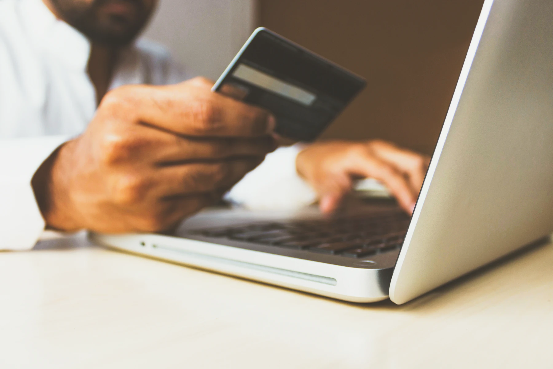 Persona pagando con tarjeta una compra en una tienda online desde el portátil